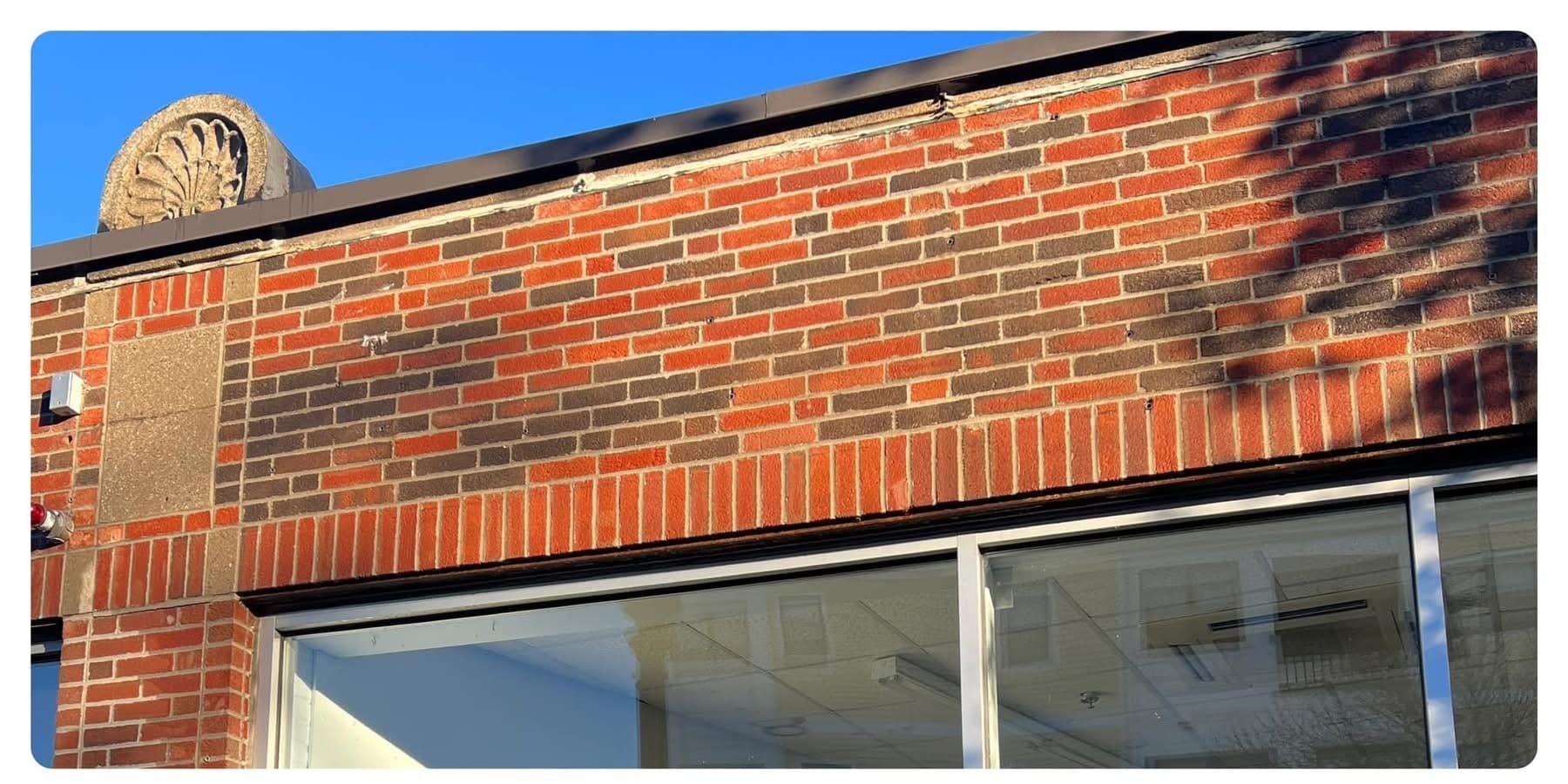 The same storefront brick band after graffiti removal, clean and evenly coloured above the windows