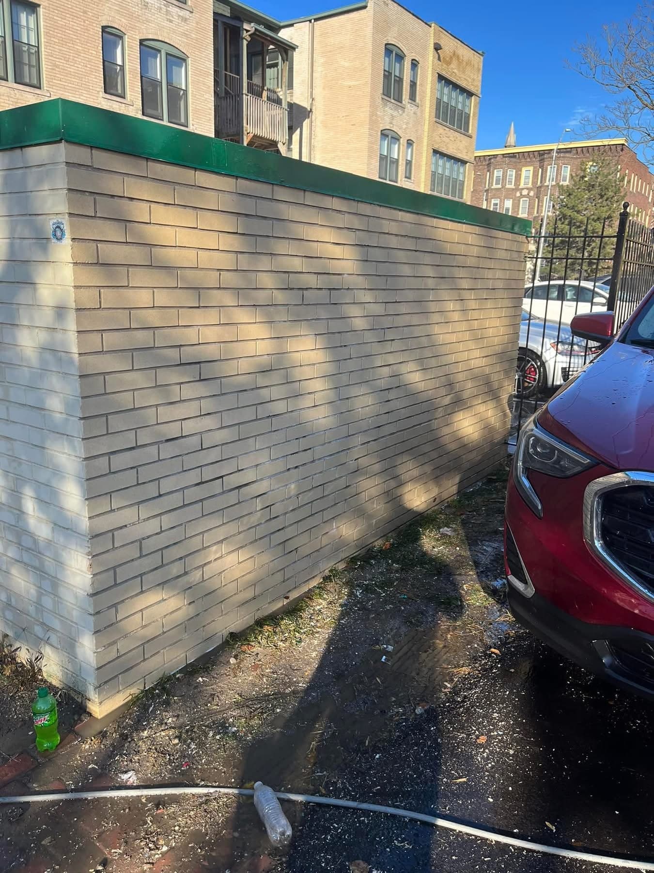 The same tan block wall after graffiti removal, back to clean uniform masonry with no shadow of the tag