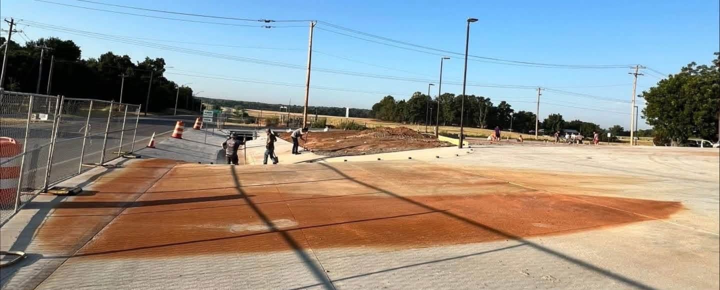 Concrete apron with orange rust staining spreading from the soil edge across several slab joints
