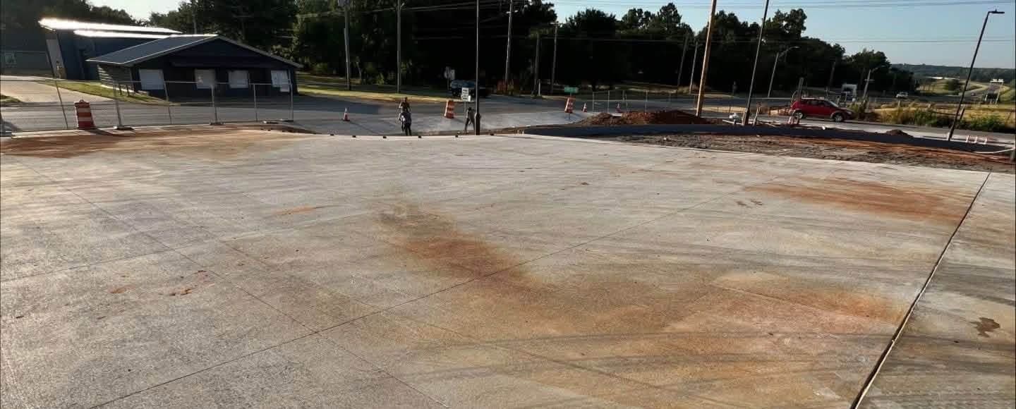 Commercial parking slab showing broad pale orange rust and mineral discolouration before cleaning