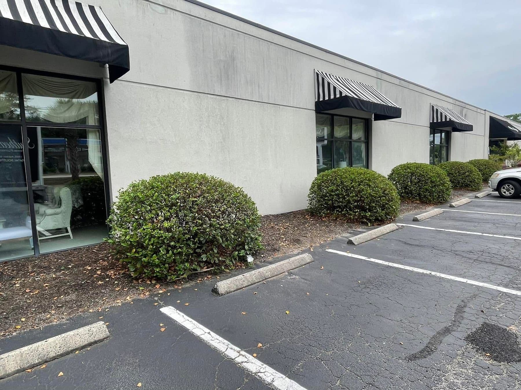 Commercial storefront elevation with black awnings and a clean parking lot frontage