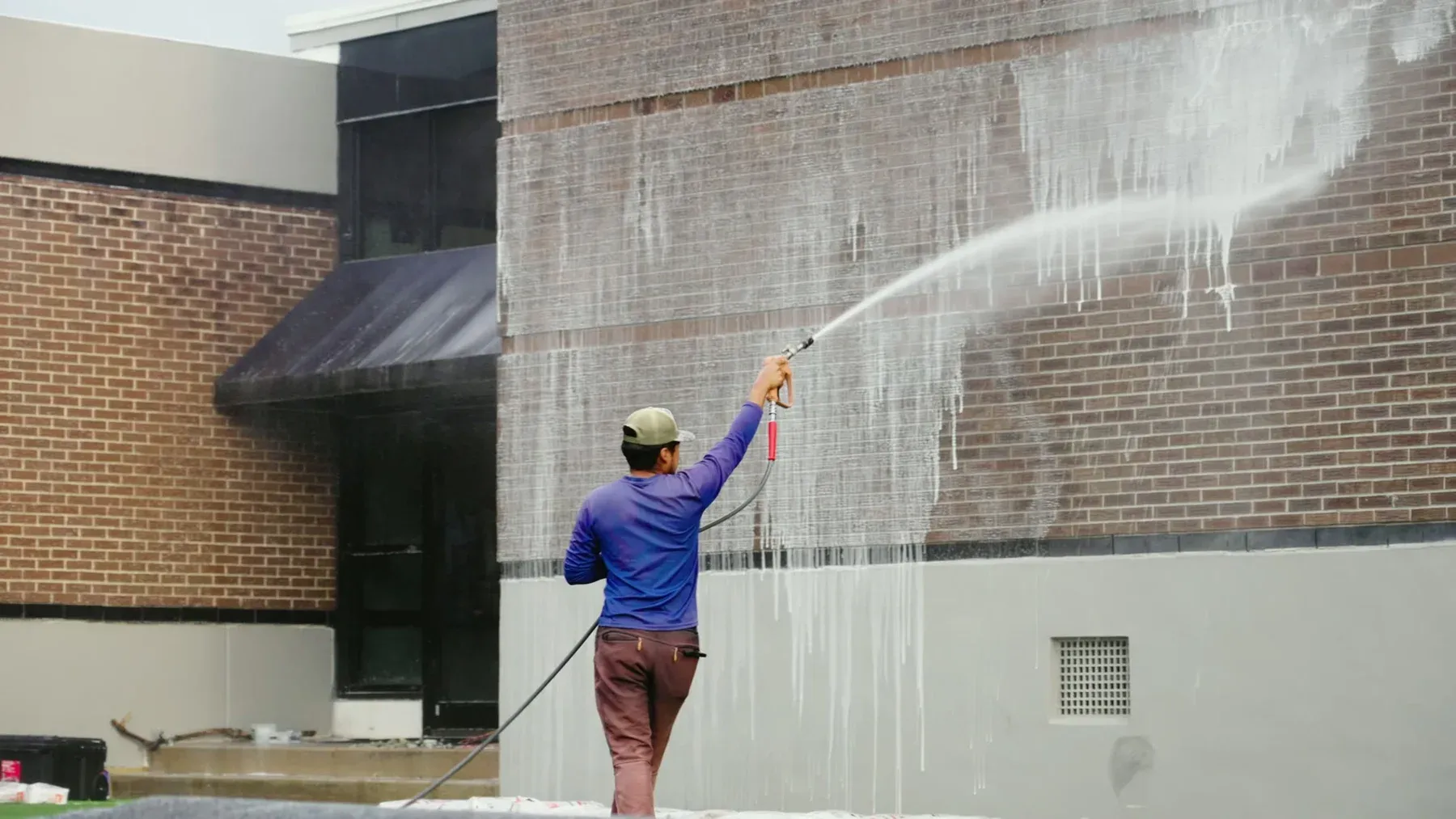 Cleaning solution running down a commercial brick facade during a ground-based soft wash in Charleston, SC