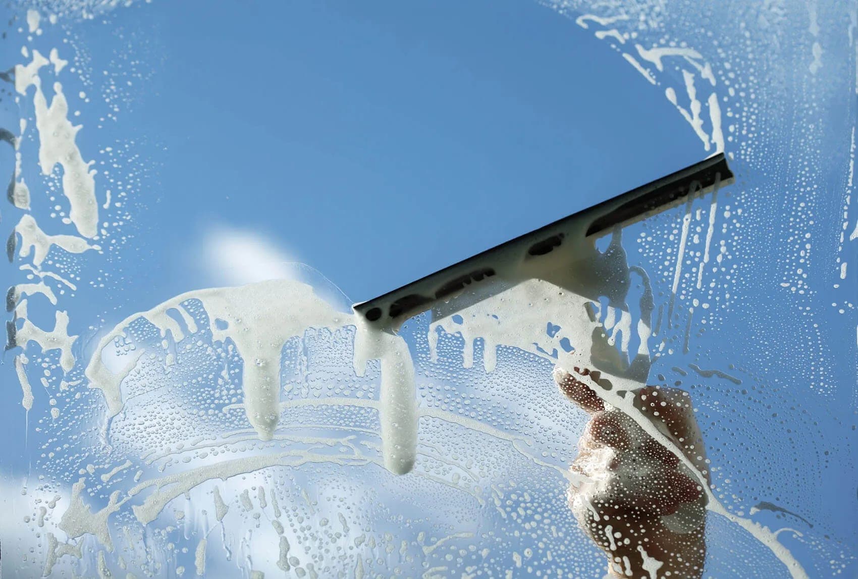 Soapy commercial storefront glass being squeegeed clean in Charleston, SC